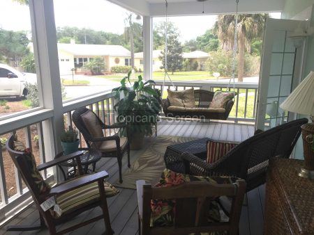 Beautiful screened in porch area with furniture and a porch swing