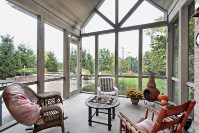 A sunroom with floor-to-ceiling windows, surrounded by a beautiful natural landscape