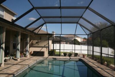 A pool enclosure with dark beams surrounding a backyard pool in Countryside, FL